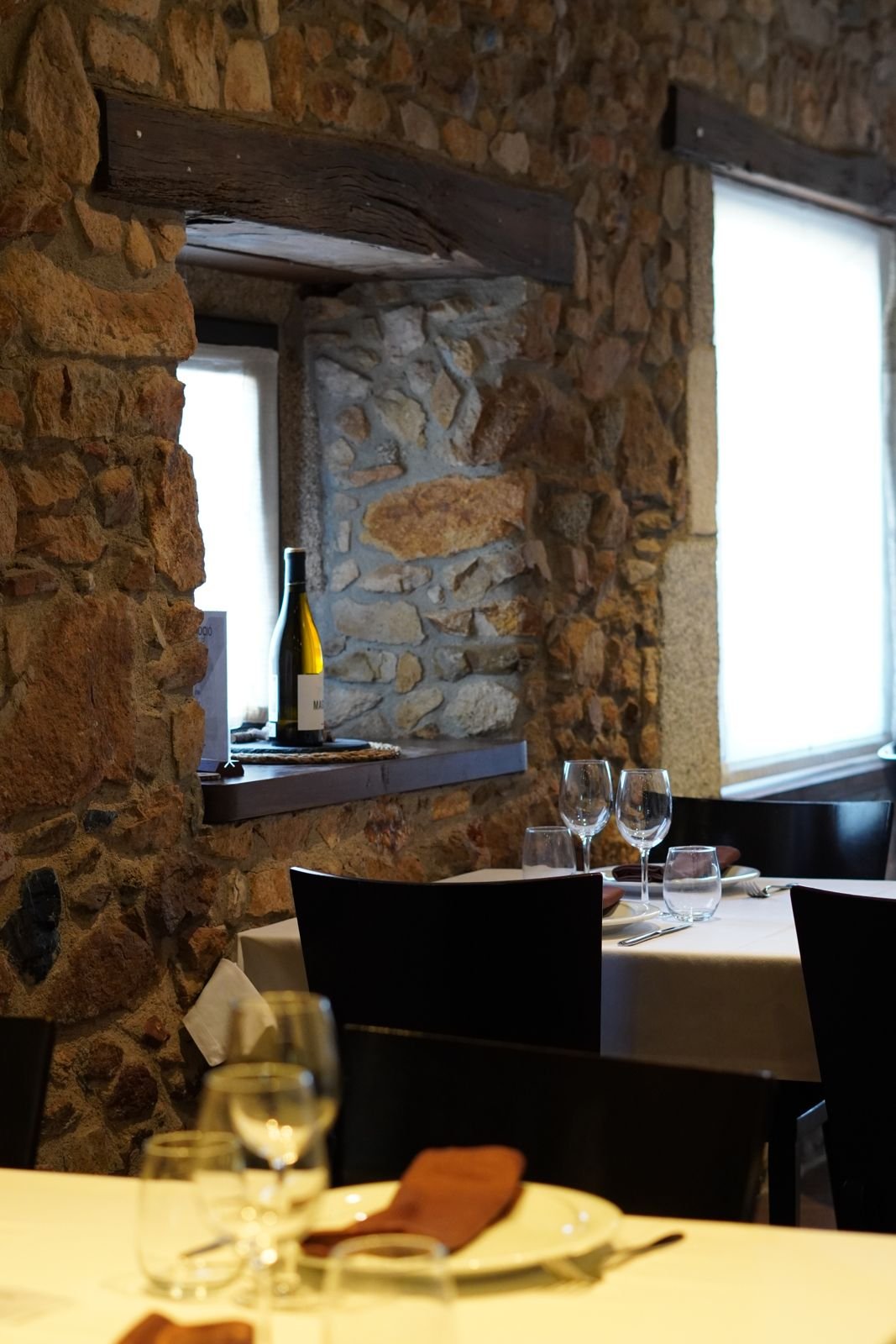 Mesa junto a la ventana con muro de piedra en Can Casellas